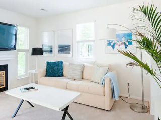 A clean and minimalist living room with a comfortable sofa, modern decor, and a large window allowing natural light